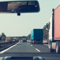 Rear view mirror looking at delivery trucks